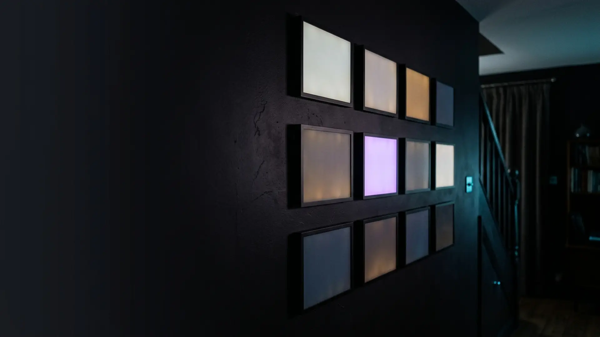 A showroom wall of televisions each glowing a different colour
